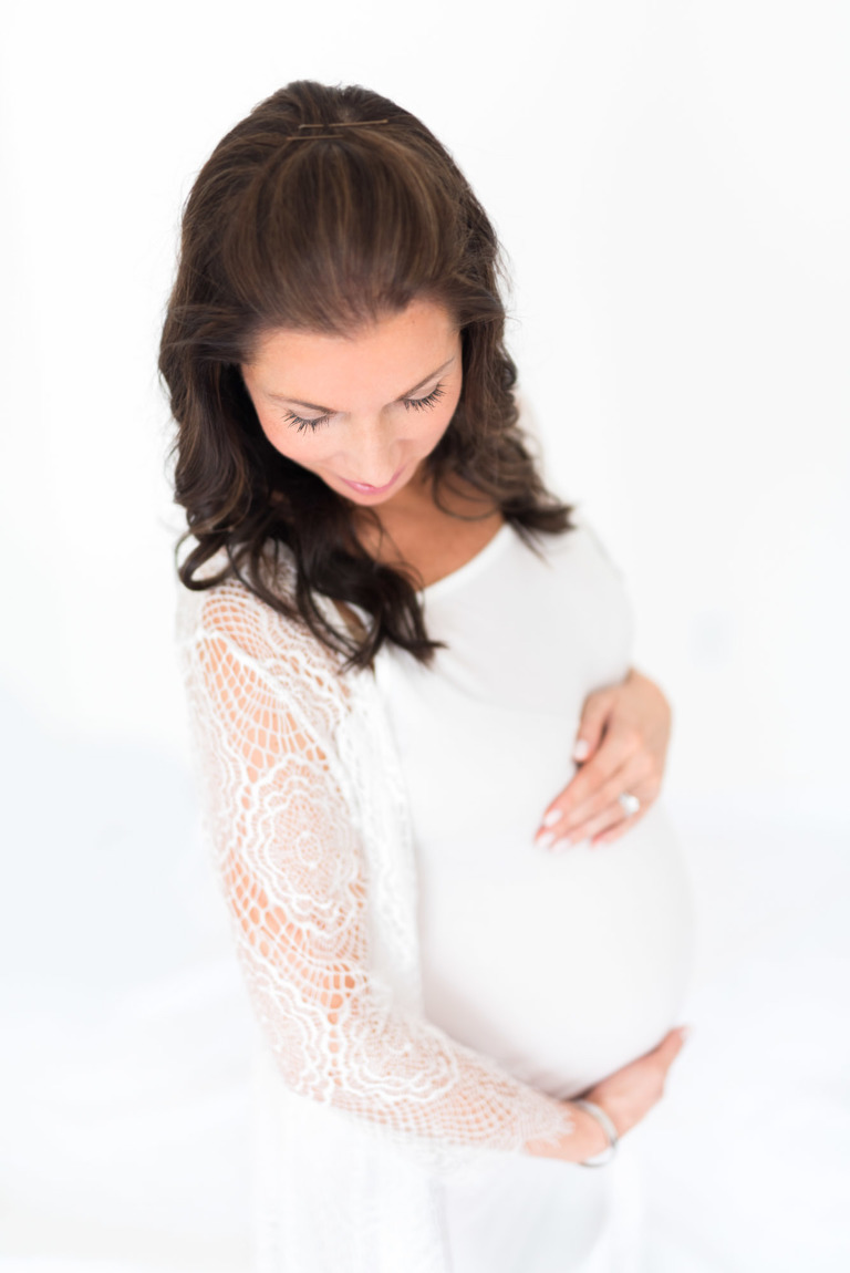 Oahu Maternity Photographer | Best Honolulu Photographer | studio pregnant woman looking down while holding stomach