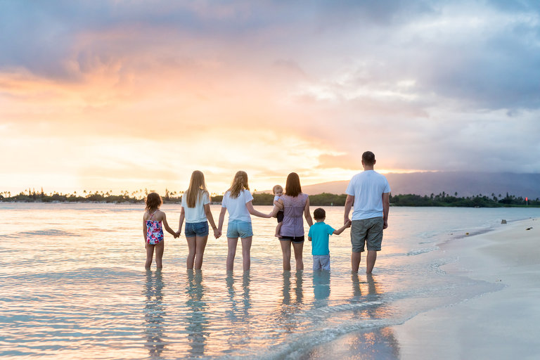 Oahu Family Photographer | Honolulu Beach family session | Family holding hands on beach watching Hawaii sunset